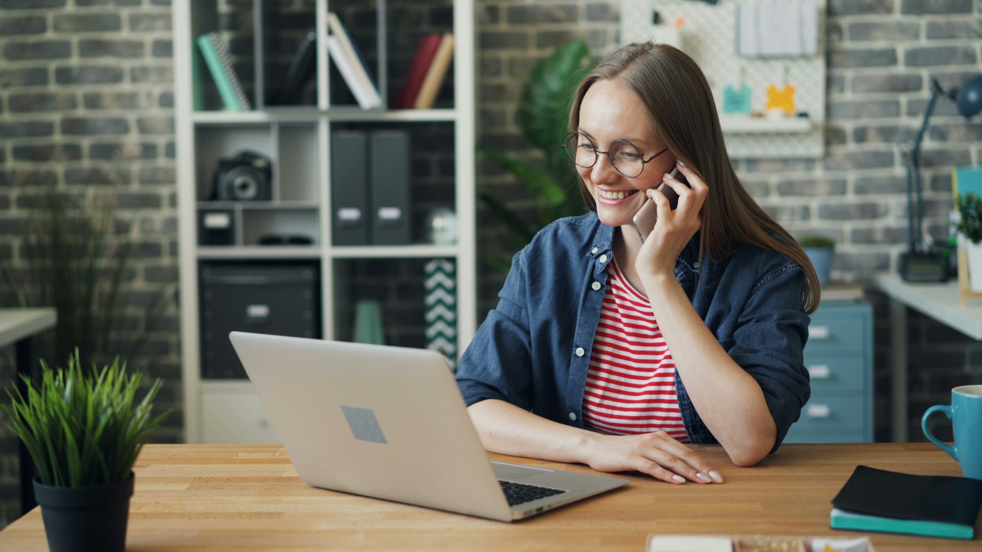 Professional in front of laptop on her cell phone